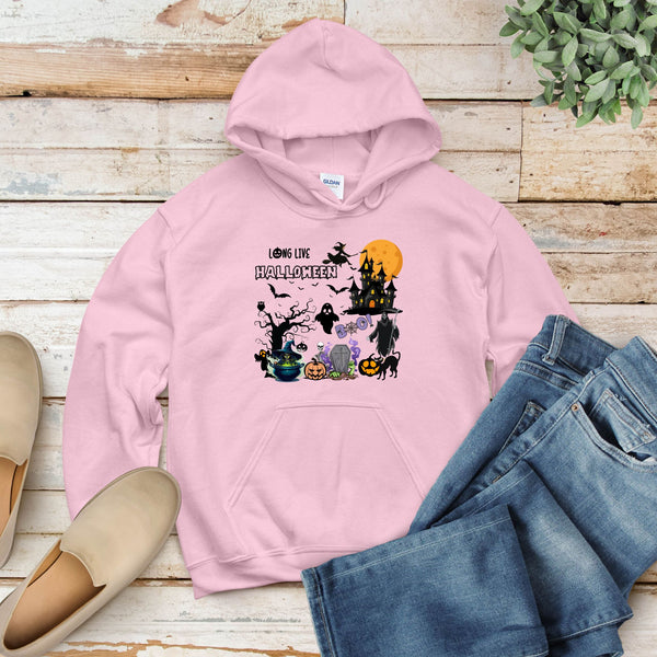 A pink hoodie with a Halloween-themed graphic design, including a castle, bats, pumpkins, and other spooky elements, is displayed on a wooden surface alongside a pair of jeans and a pair of shoes.