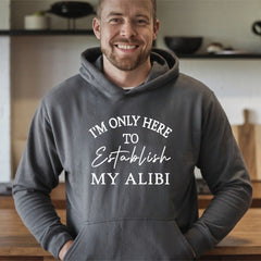 A man wearing a gray hoodie with the text "I'M ONLY HERE TO ESTABLISH MY ALIBI" printed on it.