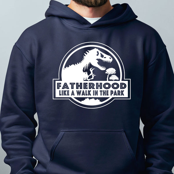 A navy blue hoodie with a graphic design featuring a dinosaur and the text "FATHERHOOD LIKE A WALK IN THE PARK".