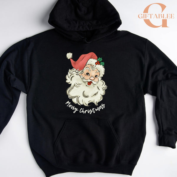 A black hoodie with a graphic of a smiling Santa Claus wearing a red hat and the text "Merry Christmas" printed on it.