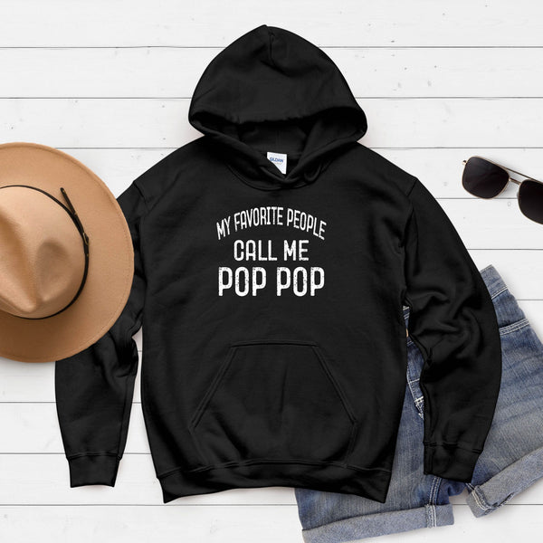 A black hoodie with the text "My favorite people call me pop pop" printed on it, along with a pair of sunglasses and a hat.