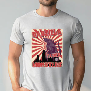 A man wearing a gray t-shirt with a graphic design featuring a large image of a Godzilla-like creature and the text "DADZILLA FATHER OF MONSTERS" printed on it.