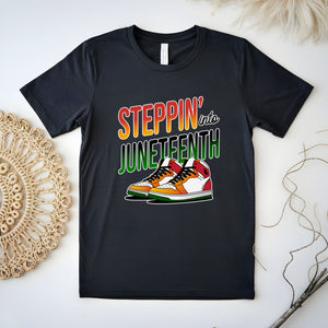 A black t-shirt with a graphic design featuring a pair of colorful sneakers and the text "StepPIN' into JUNEFTH" printed on it.