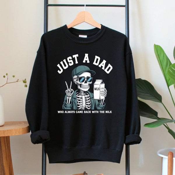 A black sweatshirt with a graphic design depicting a skeleton wearing sunglasses and holding a carton of milk, along with the text "Just a Dad" and "Who always came back with the milk".