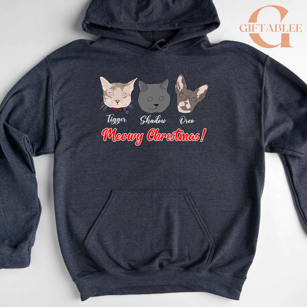 A gray hoodie with a graphic design featuring three cartoon cat faces and the text "Meowy Christmas!"