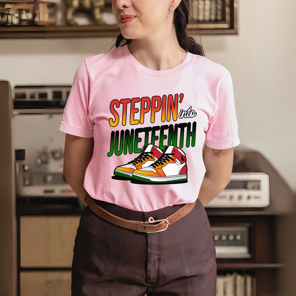 A woman wearing a pink t-shirt with a graphic design of a sneaker and the text "StepPIN' into JUNEFTH" printed on it.