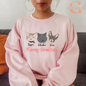 A woman wearing a pink sweatshirt with a graphic design of three cat faces and the text "Meowy Christmas!" printed on it.
