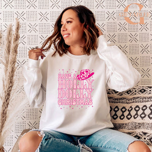 A woman wearing a white sweatshirt with a pink and white design and text, sitting on a patterned couch.