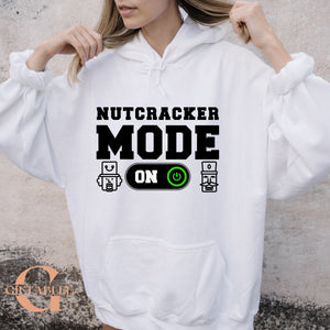 A person wearing a white hoodie with the text "NUTCRACKER MODE ON" printed on it.