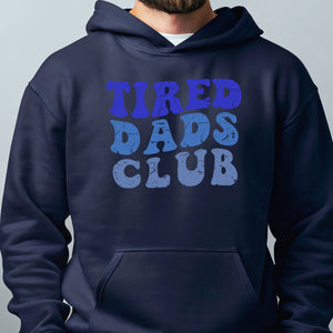 A man wearing a navy blue hoodie with the text "TIRED DAD'S CLUB" printed on it.