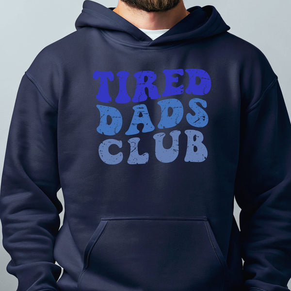 A man wearing a navy blue hoodie with the text "TIRED DAD'S CLUB" printed on it.