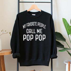 A black sweatshirt with white text printed on it, hanging on a wooden hanger.