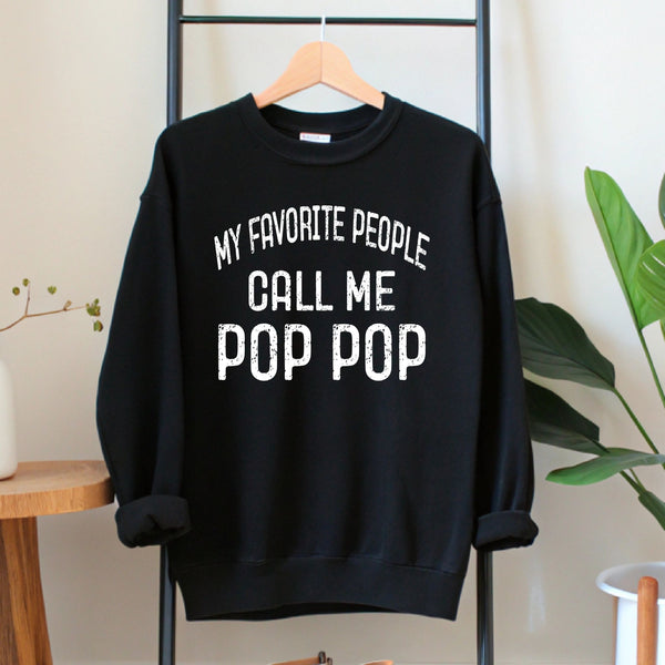 A black sweatshirt with white text printed on it, hanging on a wooden hanger.