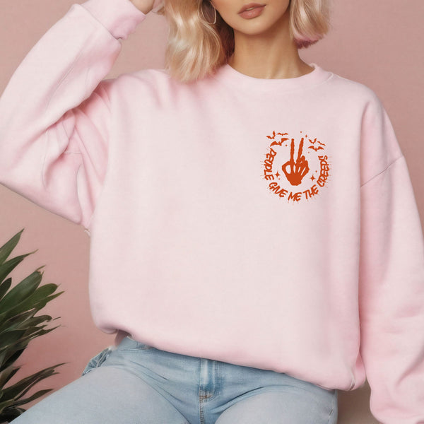 A woman wearing a pink sweatshirt with an orange graphic on it.