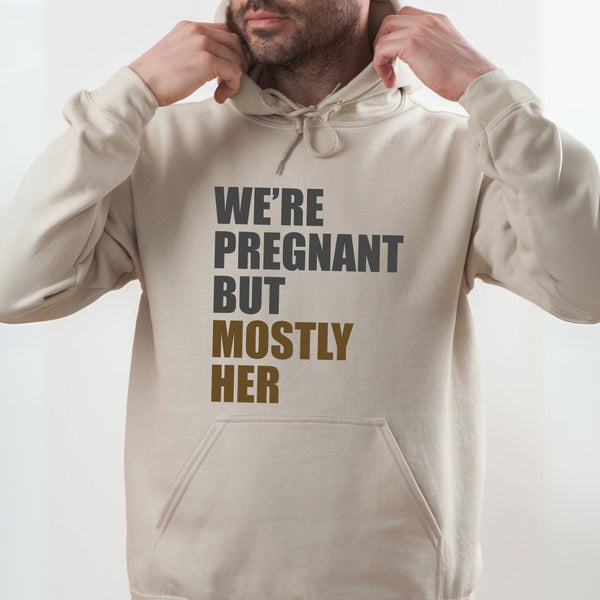 A man wearing a beige hoodie with text printed on it.