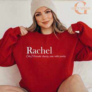 A woman wearing a red sweater and a white beanie is smiling and posing for the camera.