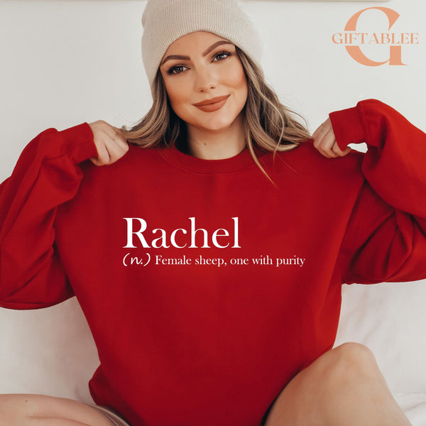 A woman wearing a red sweater and a white beanie is smiling and posing for the camera.