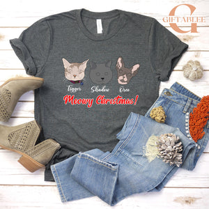 A gray t-shirt with a graphic design of three cat faces and the text "Meowy Christmas!" printed on it, along with a pair of jeans and boots.