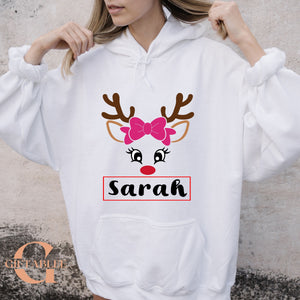 A woman wearing a white hoodie with a graphic design of a reindeer's face and the name "Sara" printed on it.