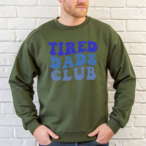 A man wearing a green sweatshirt with the text "TIRED DAD'S CLUB" printed on it.
