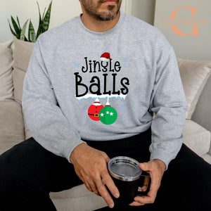 A man wearing a gray sweatshirt with the text "Jingle Balls" printed on it, sitting on a couch and holding a black mug.