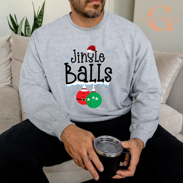 A man wearing a gray sweatshirt with the text "Jingle Balls" printed on it, sitting on a couch and holding a black mug.