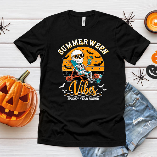 a black t-shirt with a Halloween-themed graphic design, including a skeleton riding a bicycle, a jack-o-lantern, and the text "Summer Ween Vibes Spooky Year Round".