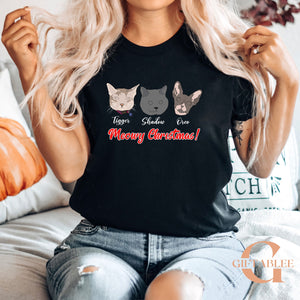 A woman wearing a black t-shirt with a graphic design of three cat faces and the text "Meowy Christmas!" printed on it.