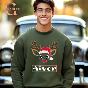 A smiling young man wearing a green sweater with a reindeer and Santa hat design, standing in front of a car.
