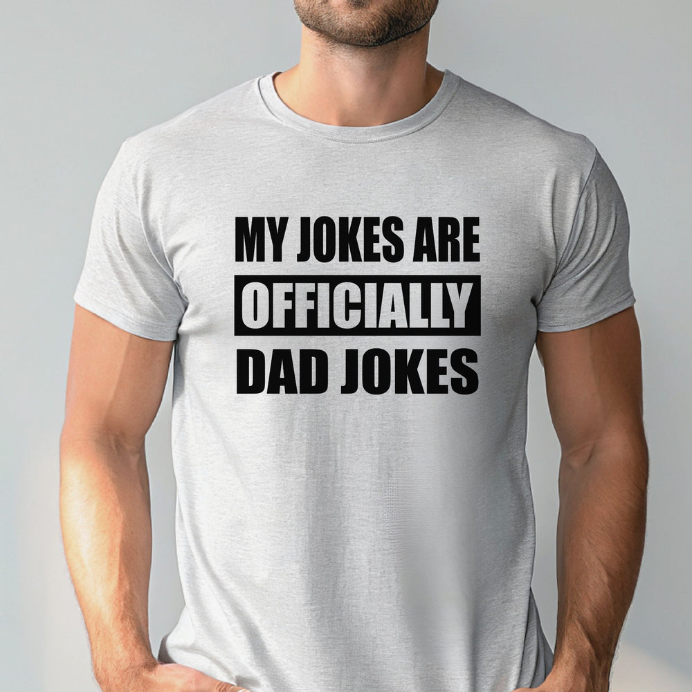 A man wearing a gray t-shirt with the text "MY JOKES ARE OFFICIALLY DAD JOKES" printed on it.