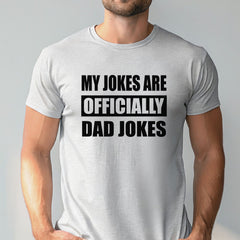 A man wearing a gray t-shirt with the text "MY JOKES ARE OFFICIALLY DAD JOKES" printed on it.