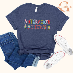 a casual outfit consisting of a blue t-shirt with a nutcracker crew design, a pair of blue jeans, and white sneakers.