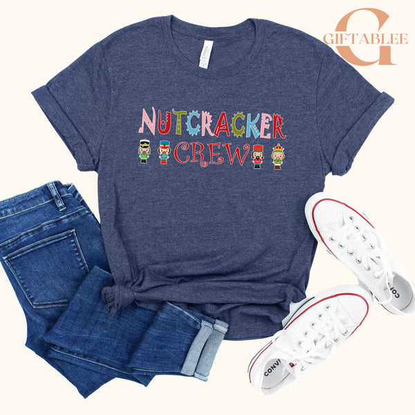 a casual outfit consisting of a blue t-shirt with a nutcracker crew design, a pair of blue jeans, and white sneakers.
