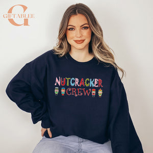 A woman wearing a navy blue sweatshirt with the text "NUTCRACKER CREW" printed on it.