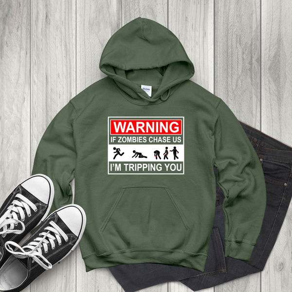 A pair of green hooded sweatshirt with a warning graphic and text, along with a pair of black and white sneakers, laid out on a wooden surface.