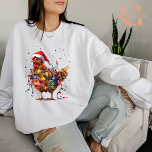 A woman wearing a white sweatshirt with a colorful illustration of a chicken wearing a Santa hat and surrounded by Christmas lights.