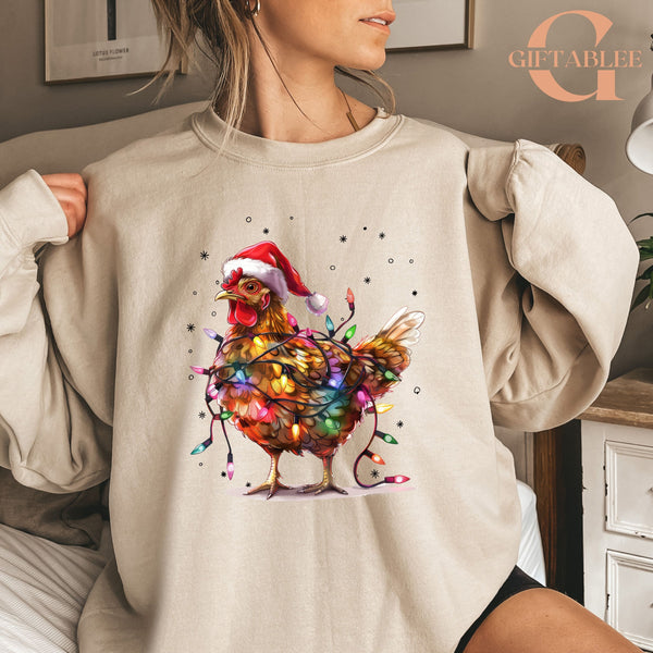 A woman is wearing a beige sweater with a colorful illustration of a chicken wearing a Santa hat and surrounded by Christmas lights.