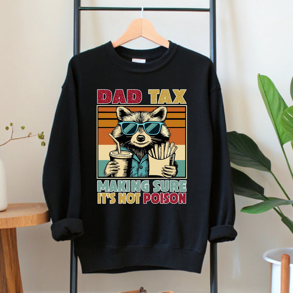 A black sweatshirt with a graphic design depicting a raccoon wearing sunglasses and holding a cup of fries, along with the text "DAD TAX MAKING SURE IT'S NOT POISON".