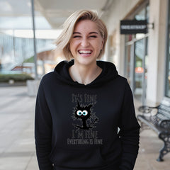 A smiling woman wearing a black hoodie with a cat graphic and text printed on it.