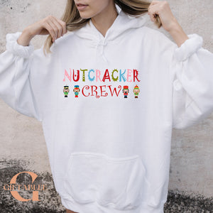 A woman wearing a white hoodie with the text "NUTCRACKER CREW" printed on it.