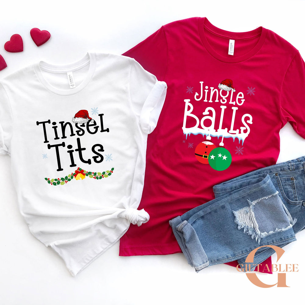 a pair of Christmas-themed t-shirts, one white and one red, along with a pair of jeans, all laid out on a white background.