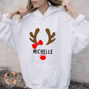 A woman wearing a white hoodie with a graphic design of a reindeer and the name "Michele" printed on it.