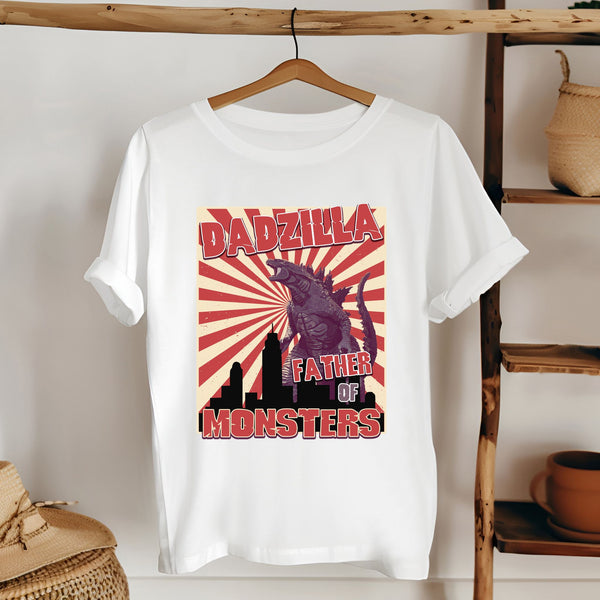 A white t-shirt with a graphic design featuring a large, menacing-looking creature resembling a dragon or monster, along with the text "DADZILLA" and "FATHER OF MONSTERS".