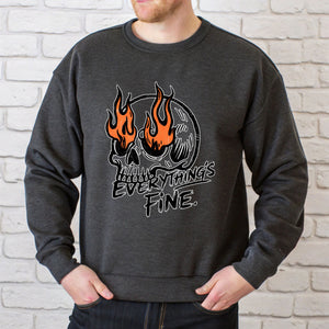 A man wearing a gray sweatshirt with a graphic design featuring a skull with flames and the text "EVERYTHING IS FINE" printed on it.