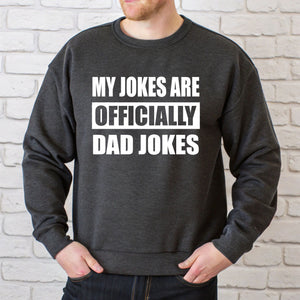 A man wearing a grey sweatshirt with the text "MY JOKES ARE OFFICIALLY DAD JOKES" printed on it.