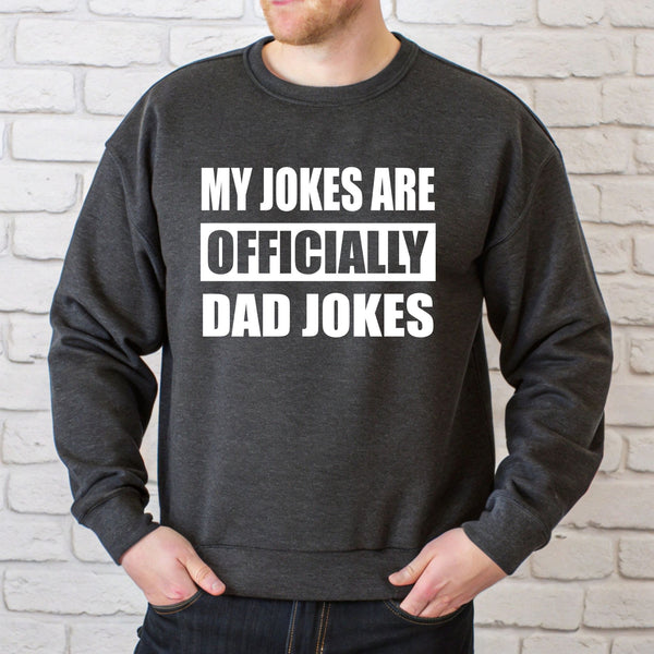 A man wearing a grey sweatshirt with the text "MY JOKES ARE OFFICIALLY DAD JOKES" printed on it.