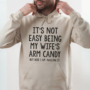 A man wearing a beige hoodie with a humorous text printed on it.