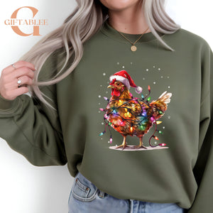 A woman wearing a green sweatshirt with a colorful illustration of a chicken wearing a Santa hat and surrounded by Christmas lights.
