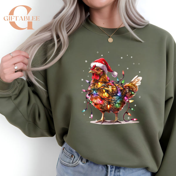 A woman wearing a green sweatshirt with a colorful illustration of a chicken wearing a Santa hat and surrounded by Christmas lights.