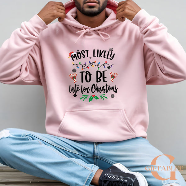 A man wearing a pink hoodie with the text "Most likely to be late for Christmas" printed on it.